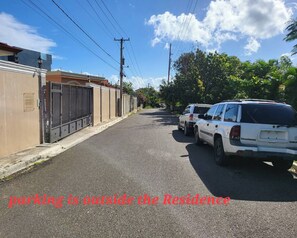 A residential street with parked cars and a gated entrance. - Tranquil 1-bedroom Apartment in Puerto Plata, Dominican Republic (Puerto Plata)