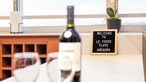 Una botella de vino y copas sobre una mesa con un cartel que dice "WELCOME TO LE FOYER FLATS AREQUIPA".
