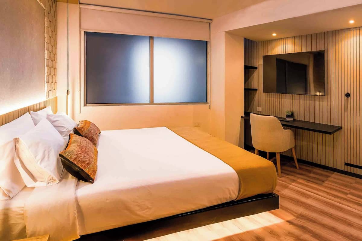 A hotel room with a bed, a desk, and a TV.