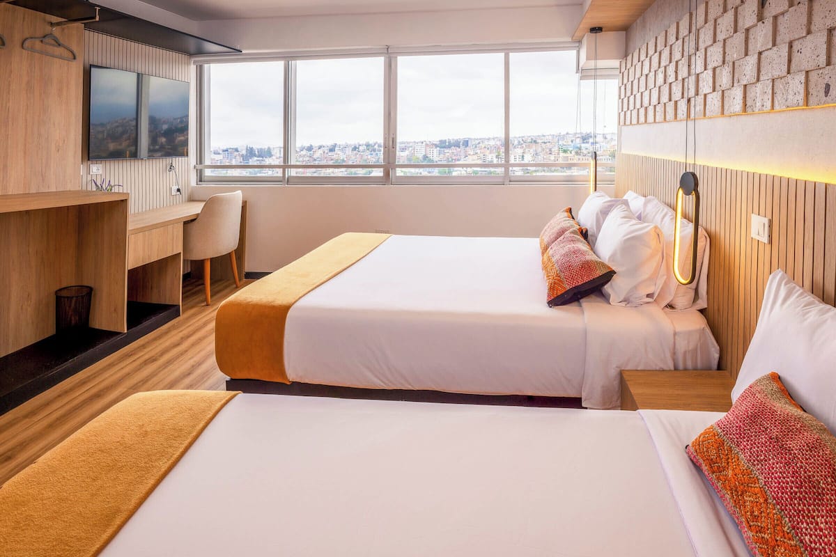 A hotel room with a large bed, a desk, and a view of the city.