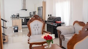 Un saló modern amb una làmpada penjant, una taula de dinar amb caires, una cuina al fons i un xarment.