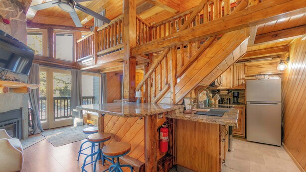 Interno di una baita in legno con angolo cottura, zona bar e scala.