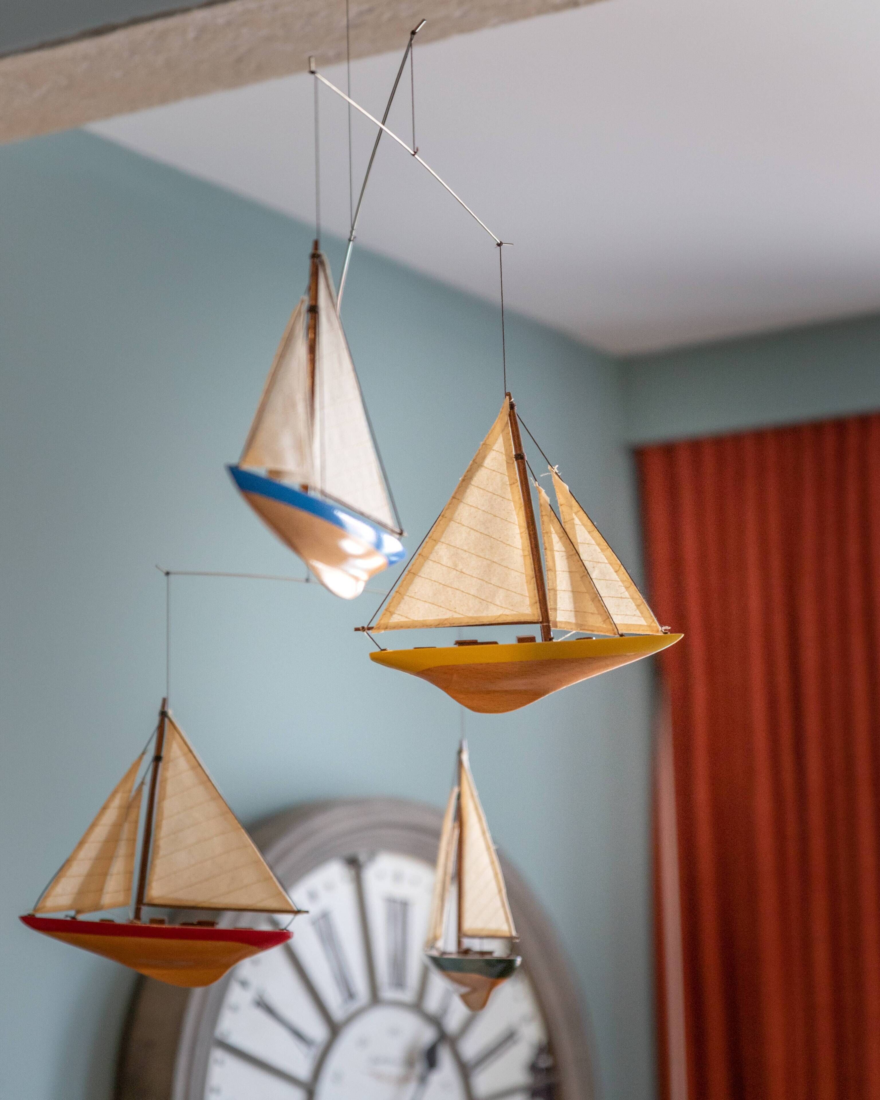 A room with a large wall clock and three hanging sailboat decorations.