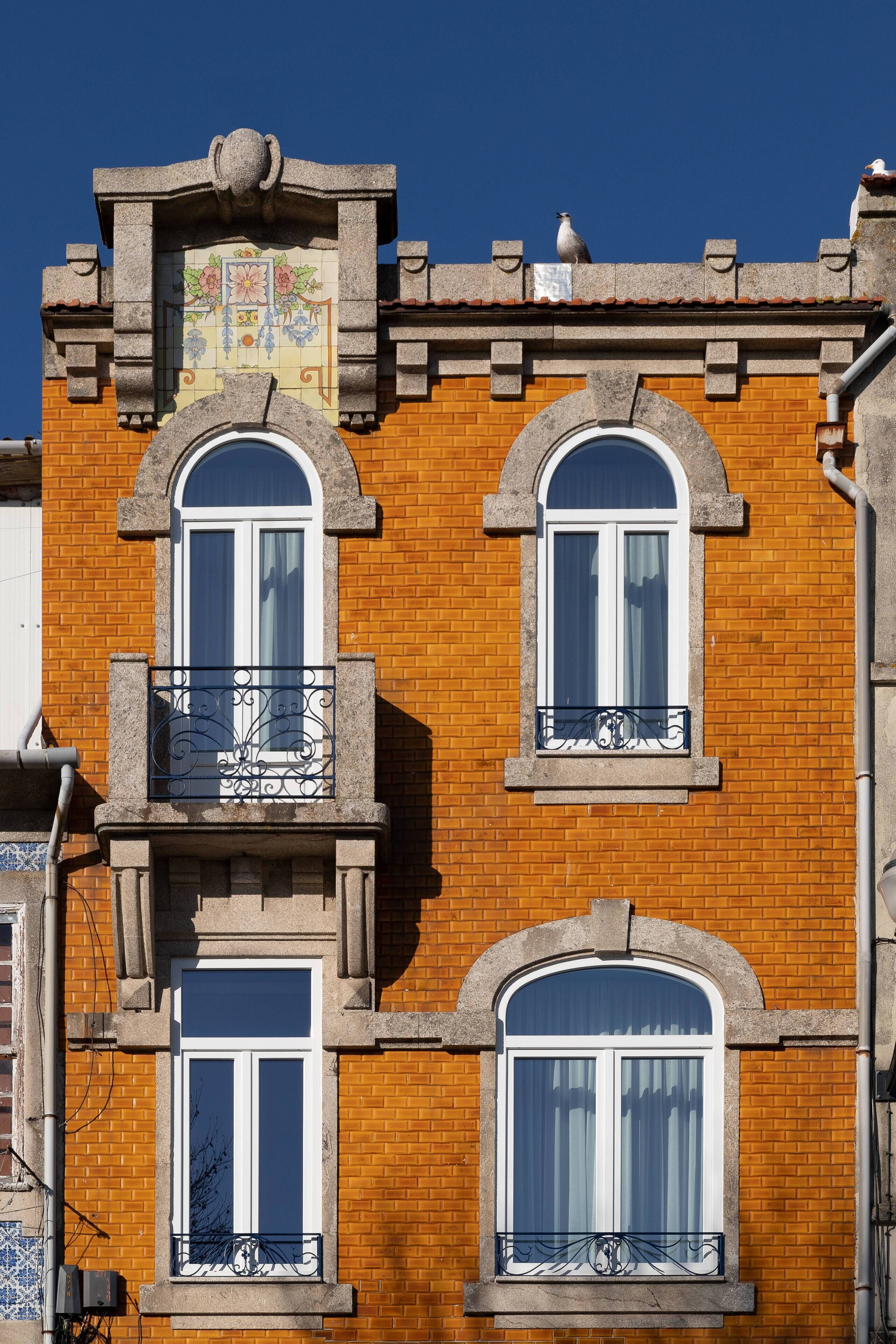 A multi-story building with a brick facade, arched windows, and decorative iron railings.