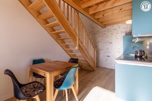Ein Holzespeisesaal mit zwei Stühlen, ein Küchenbereich mit blauer Arbeitsplatte und eine Holztreppe.