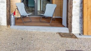 Een gebouw met een gevel van natuursteen, een houten deur en twee stoelen ervoor.