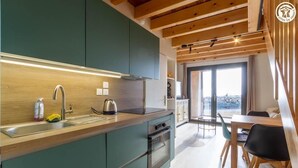 Een moderne keuken met houten kastjes, een roestvrijstalen spoelbak en een oven. Er is een eethoek met een tafel en stoelen.