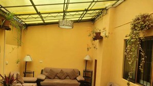 A living room with a sofa set, two side tables, floor lamps, and potted plants. - HOTEL HUAYNAPATA PARDO (Cusco)