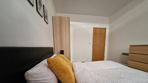 Ein Schlafzimmer mit einem Bett, einem Holzschrank, einer Tür und einer Wandleuchte.