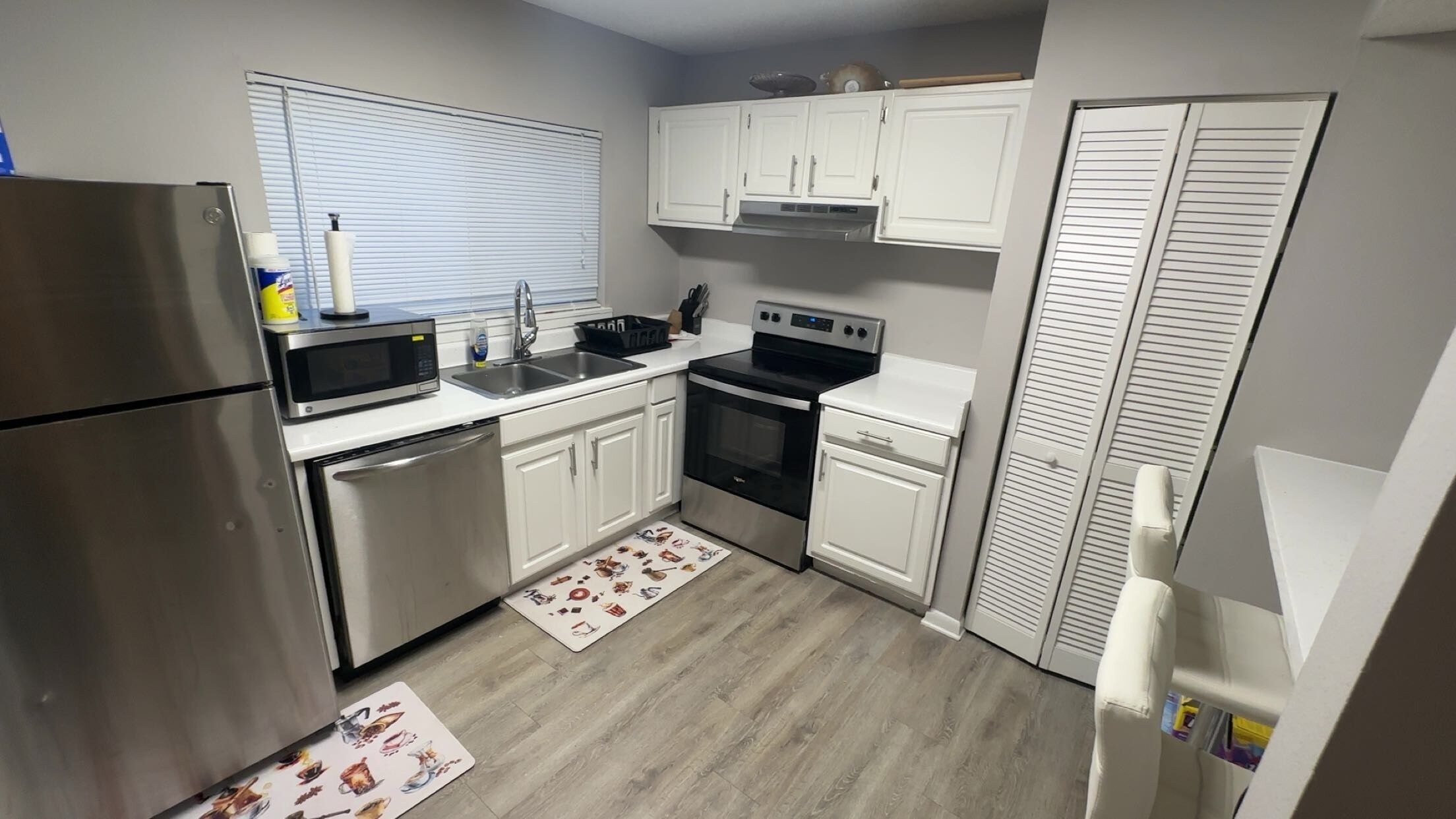 A compact kitchen with a refrigerator, microwave, sink, stove, and cabinets.