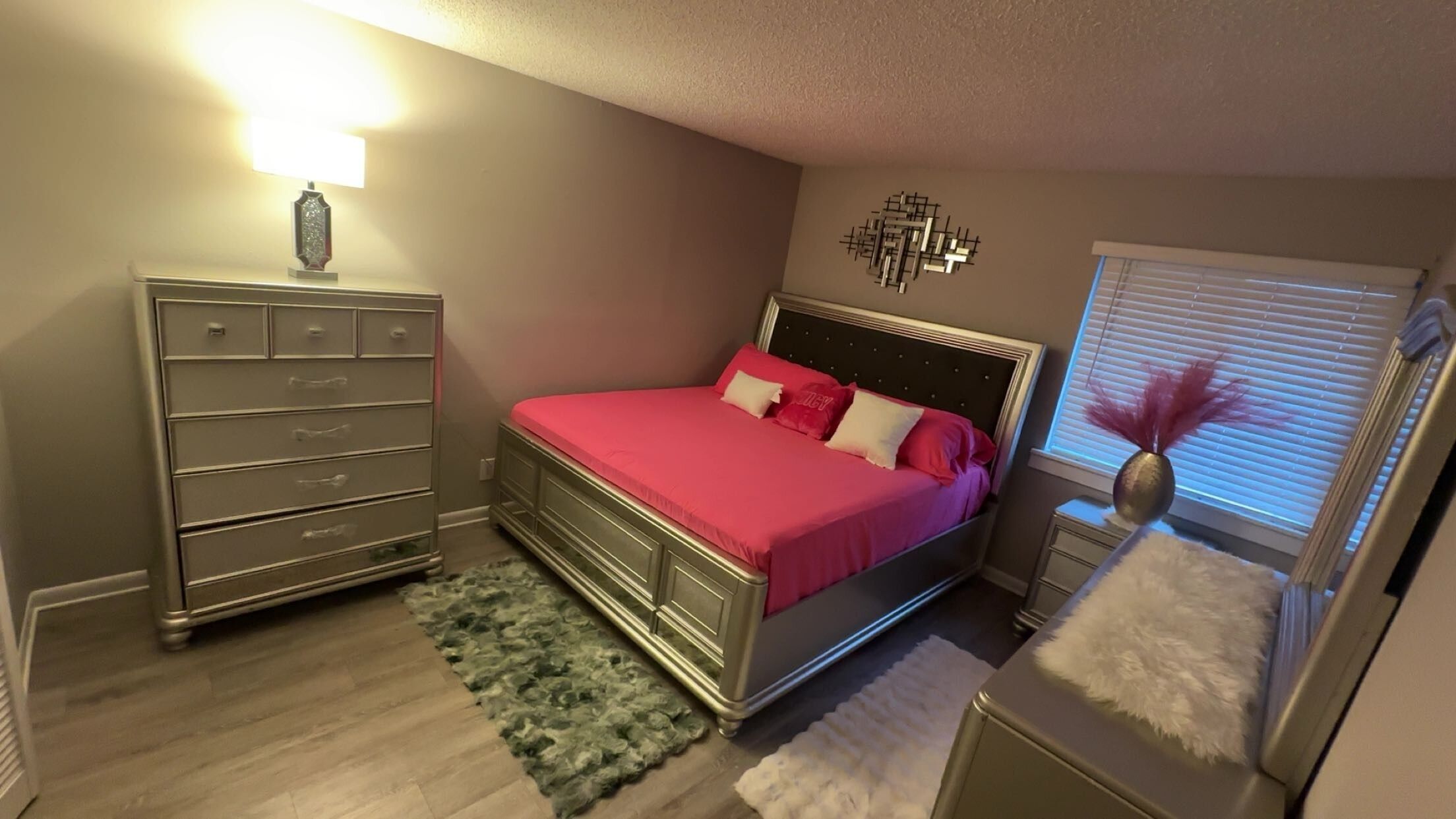 Een slaapkamer met een bed, een dressoir en een raam met jaloezieën.