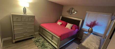 Een slaapkamer met een bed, een dressoir en een raam met jaloezieën.