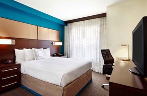 A hotel room with a large bed, a desk with a television, a chair, a nightstand, and a window with curtains. - Extended Stay America Suites - Houston - Galleria (Houston)