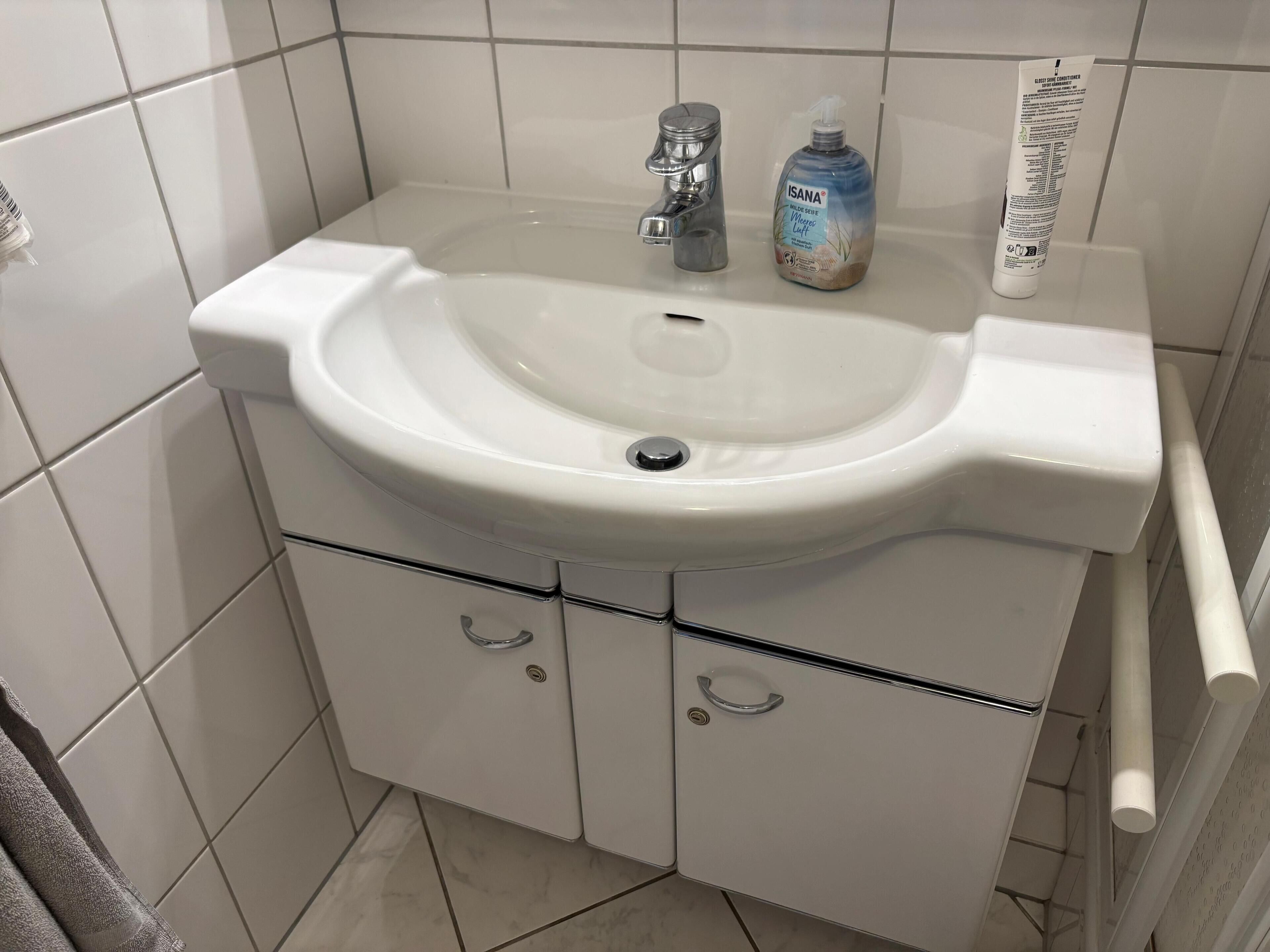 A bathroom with a white sink, a faucet, and a bottle of hand soap.