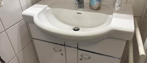 A bathroom with a white sink, a faucet, and a bottle of hand soap.