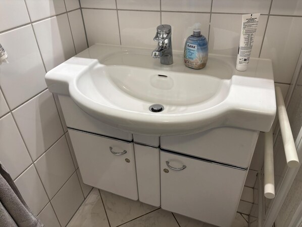 A bathroom with a white sink, a faucet, and a bottle of hand soap. - North Sea view "House An apartment 45" (Norderney)