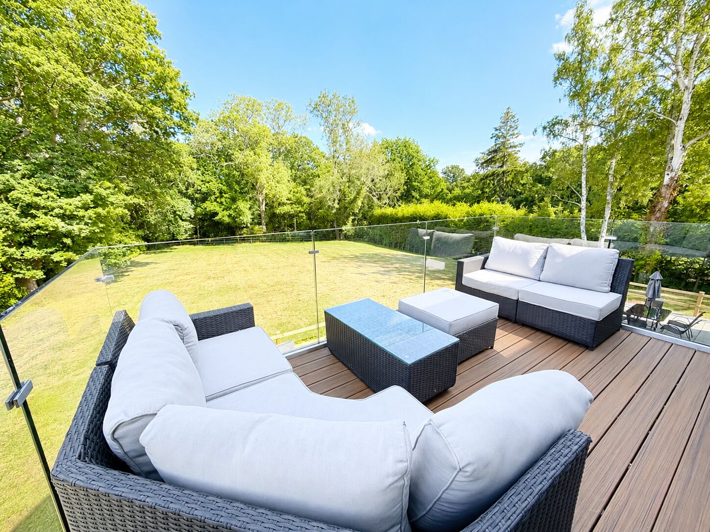 An outdoor deck with wicker furniture, including sofas and a coffee table.
