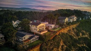 A residential area with houses on a hillside, featuring a mix of single and multi-story buildings, some with large windows and balconies. - The Salt Life - Oceanfront escape Hot tub (Lincoln City)