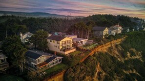 A residential area with houses on a hillside, featuring a mix of single and multi-story buildings, some with large windows and balconies. - The Salt Life - Oceanfront escape Hot tub (Lincoln City)