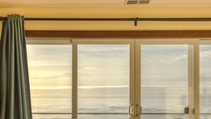 A bedroom with a large sliding glass door leading to a balcony, a bed, and a wooden floor. - The Salt Life - Oceanfront escape Hot tub (Lincoln City)