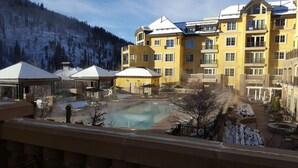 Resort com piscina, área de estar externa e montanhas ao fundo.