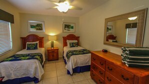 Ein Hotelzimmer mit zwei Betten, einem Nachttisch, einer Kommode und einem Deckenventilator.
