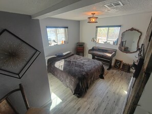 Un dormitorio con cama, escritorio, espejo y ventana.