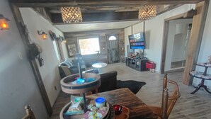 A rustic dining area with a wooden table, a bowl with snacks, and a television in the background. - Haunted 3-bedroom Mining Cabin, only 8 miles from Death Valley Park - Beatty, NV (Beatty)