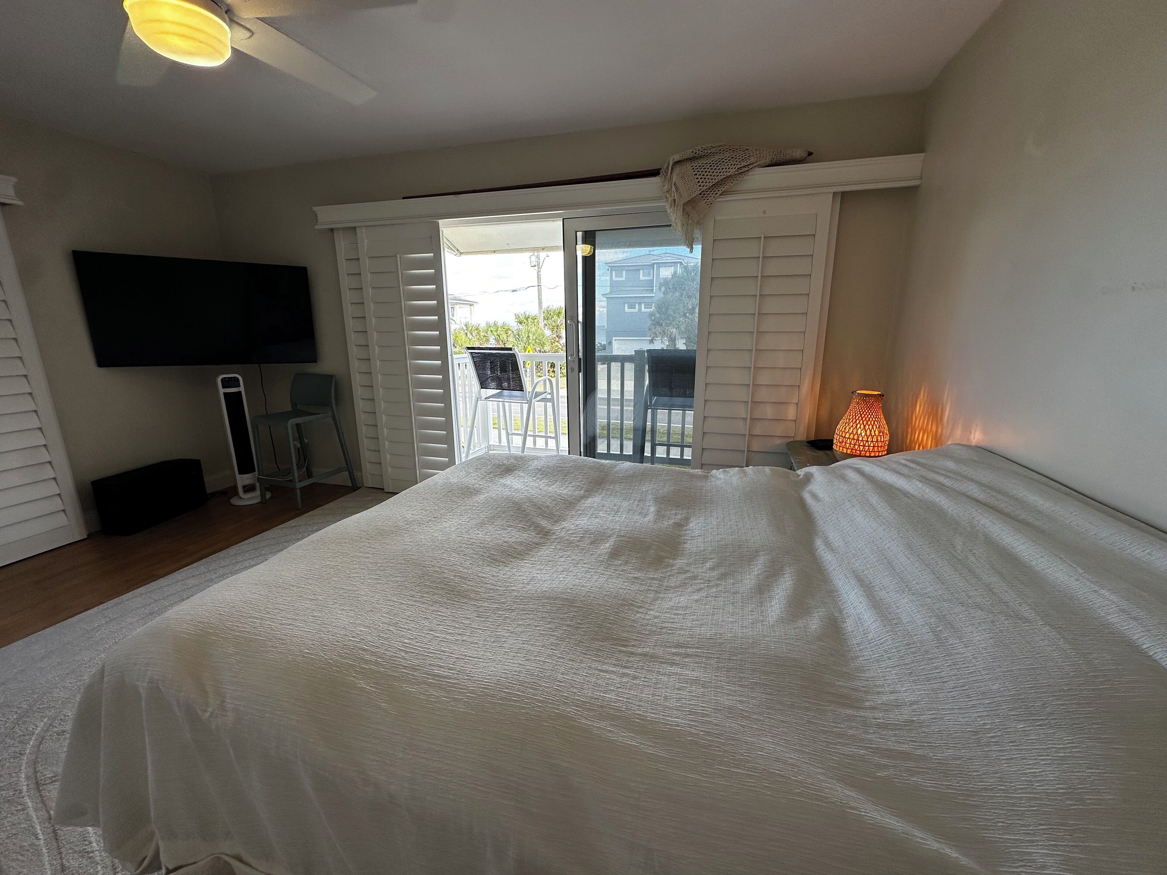 Una camera da letto con un letto, una TV, una lampada e un balcone vista esterna.