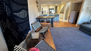 Ett modernt vardagsrum med en soffa, en matplats med bord och stolar samt ett kök i bakgrunden.