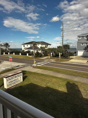 Una calle residencial con una señal de stop, un paso de peatones y un cartel que indica Lighthouse Shores Townhomes.