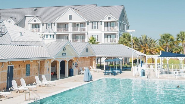 Un hotel con piscina, varios balcones y una zona exterior cubierta.