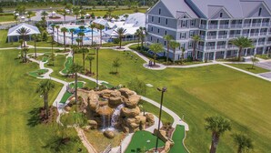 Un campo de golf con una cascada de rocas, rodeado por un hotel de varios pisos y balcones.