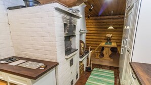 A rustic kitchen with a brick wall, wooden cabinets, a wooden countertop, and a green striped rug. - Hännänpää by Interhome (Vihti)