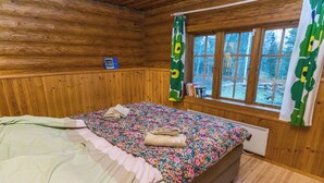 A wooden cabin bedroom with a bed, a window, and a radiator. - Hännänpää by Interhome (Vihti)