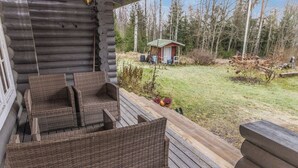 A log cabin with a wooden deck, wicker furniture, and a small shed in the background. - Hännänpää by Interhome (Vihti)