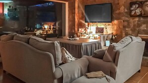 Una sala de estar acogedora con un amplio sofá, un televisor de pantalla plana en la pared y una chimenea.