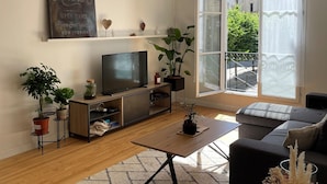 A living room with a television, sofa, coffee table, and potted plants.