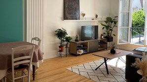 A living room with a dining table, chairs, a TV, and potted plants.