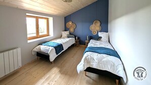 A room with two beds, a window, wooden flooring, and a ceiling with a hanging light fixture. - "Ensemble - MEYS - Gîte (MEYS)