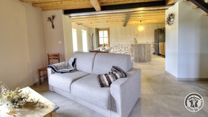 A spacious living area with a sofa, a dining table, and a kitchen in the background. - "Ensemble - MEYS - Gîte (MEYS)