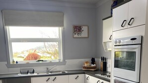 A modern kitchen with white cabinets, a built-in oven, and a window with a view of the outdoors.