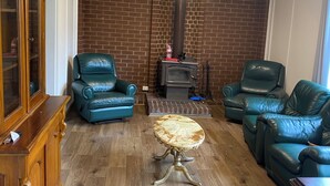 A living room with two green leather sofas, a wooden cabinet, and a fireplace.
