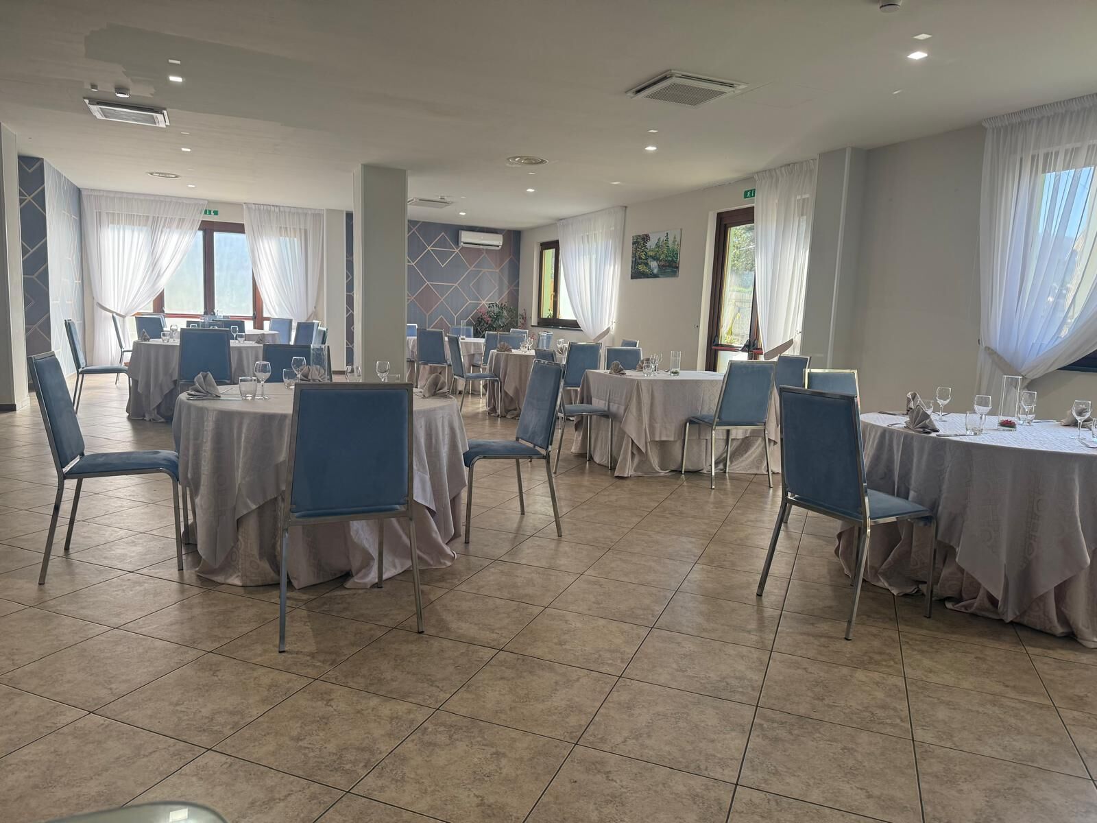 Un comedor con mesas redondas, sillas y piso de baldosas.