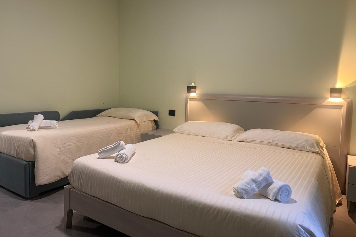 Habitación de hotel con dos camas, cada una con cabecero y mesitas de noche.
