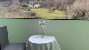 Un balcon avec une table, une chaise et un vase rempli de fleurs.