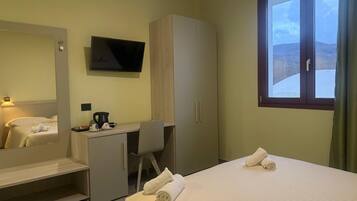 Ett hotellrum med en säng, ett skrivbord, en tv och ett fönster med utsikt.