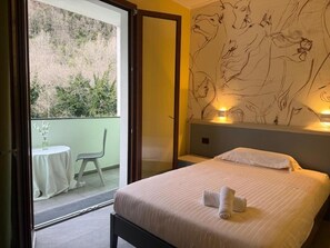 A hotel room with a bed, a balcony with a table and chair, and a wall with abstract art. - HOTEL PICCOLO PARADISO  (Latronico)