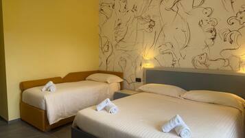 A hotel room with two beds, each with a rolled towel, a headboard, and a wall with a line drawing mural.
