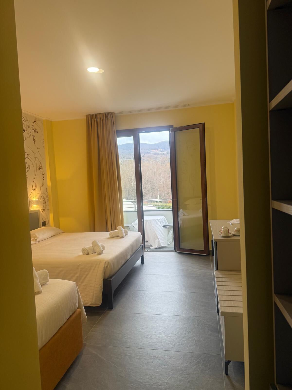 Habitación de hotel con dos camas, un escritorio y vistas al exterior.